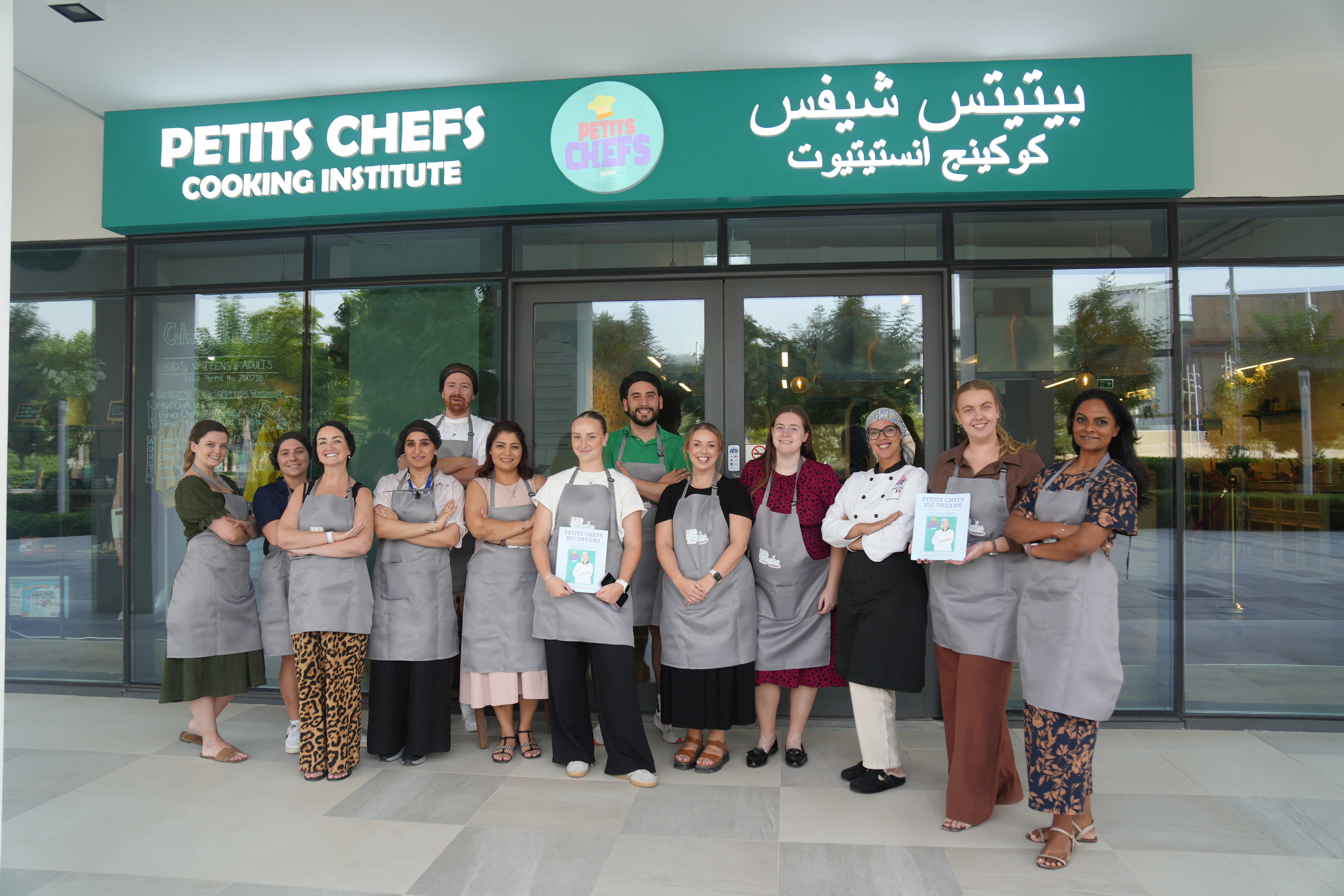 A corporate team in PCD aprons outside the Petits Chefs Cooking Institute in Dubai